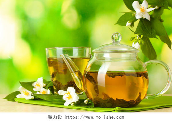 绿色背景上绿茶与茉莉花杯子和的木桌上的茶壶养生茉莉花茶